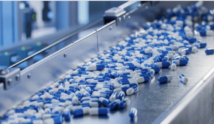 Capsules travelling along a stainless-steel conveyor